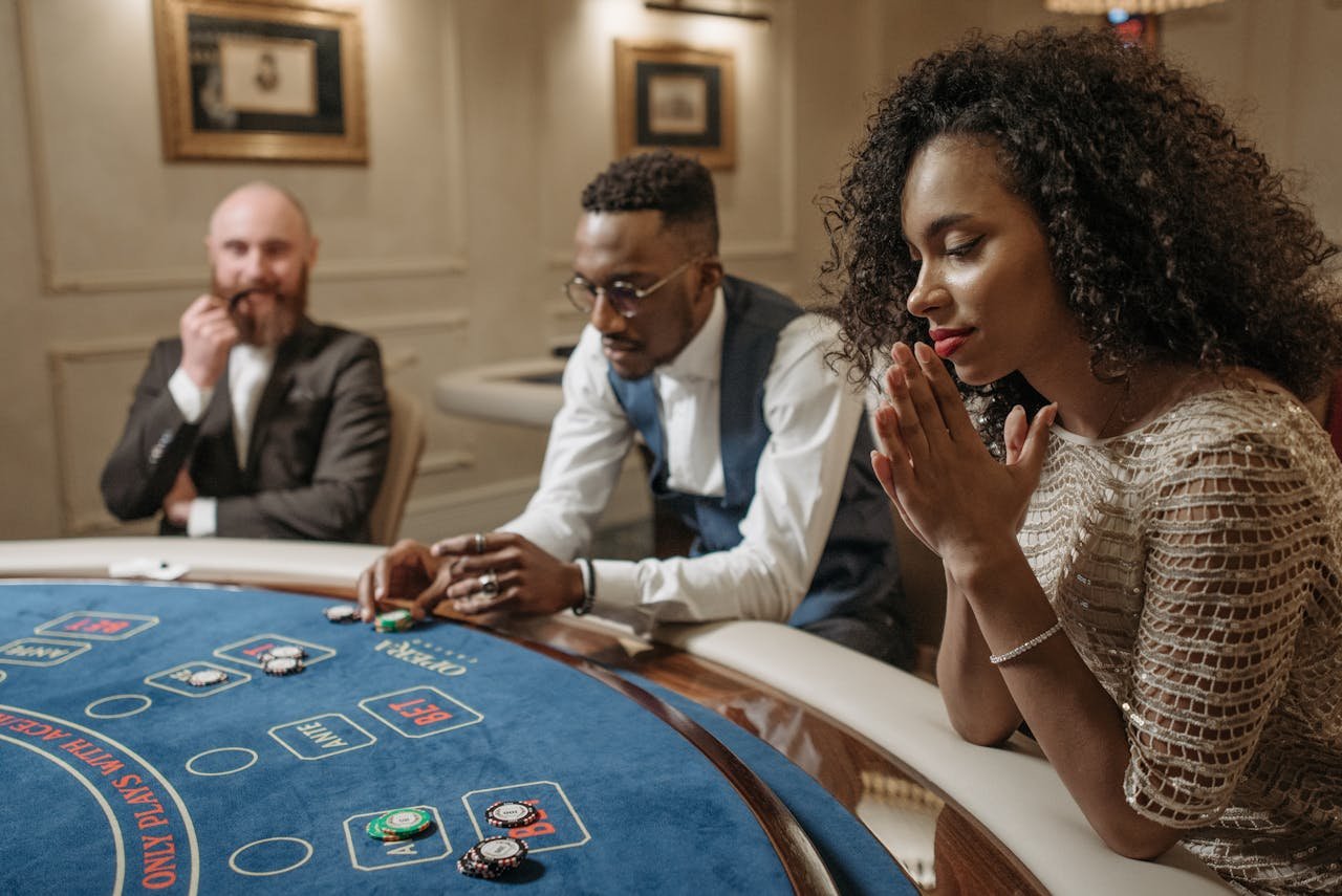 Three people engaged in a casino game, focusing on poker chips and bets at the table.