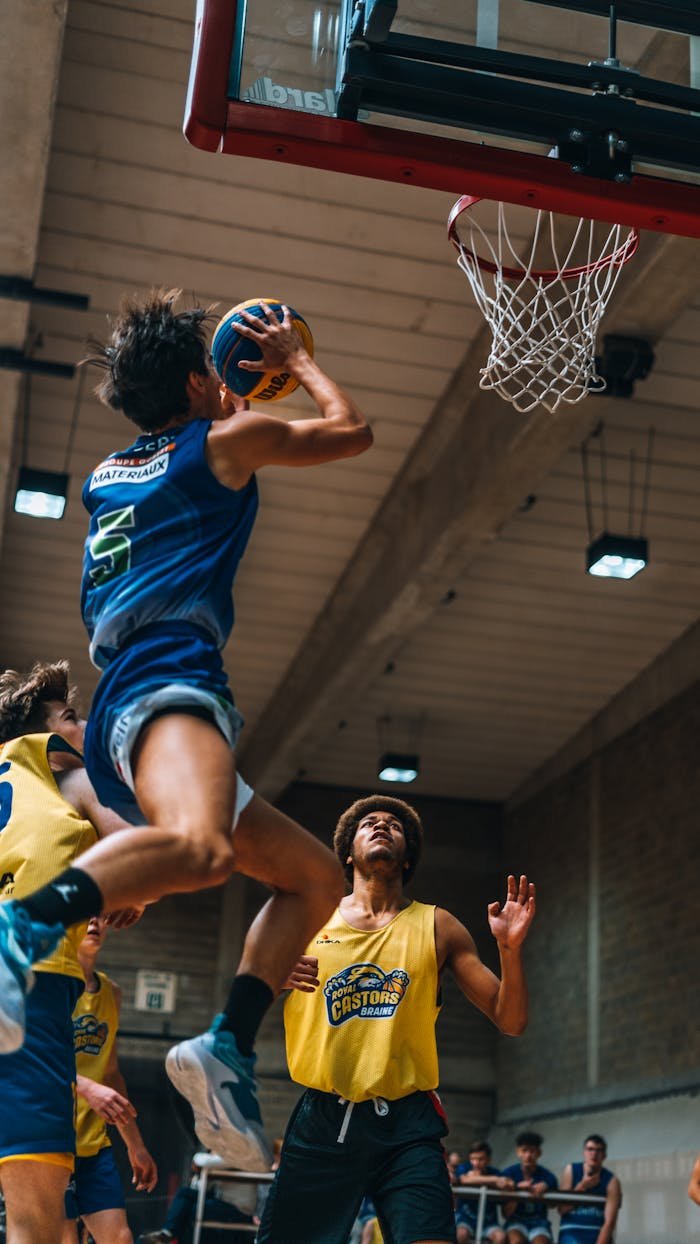 Dynamic capture of a basketball player dunking amidst competition in a sports arena.